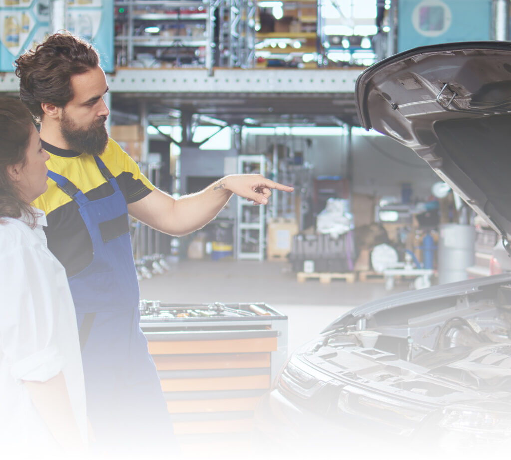 Mechanic explaining a vehicle repair to a customer, representing Route 66 warranty coverage through Compass Credit Union