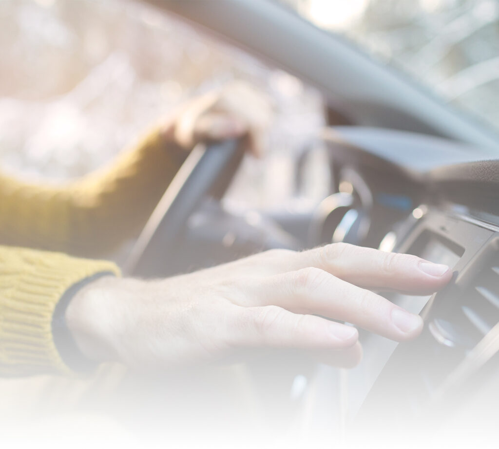 Driver reaching for car heater on a cold day, representing Route 66 warranty coverage for heating system repairs